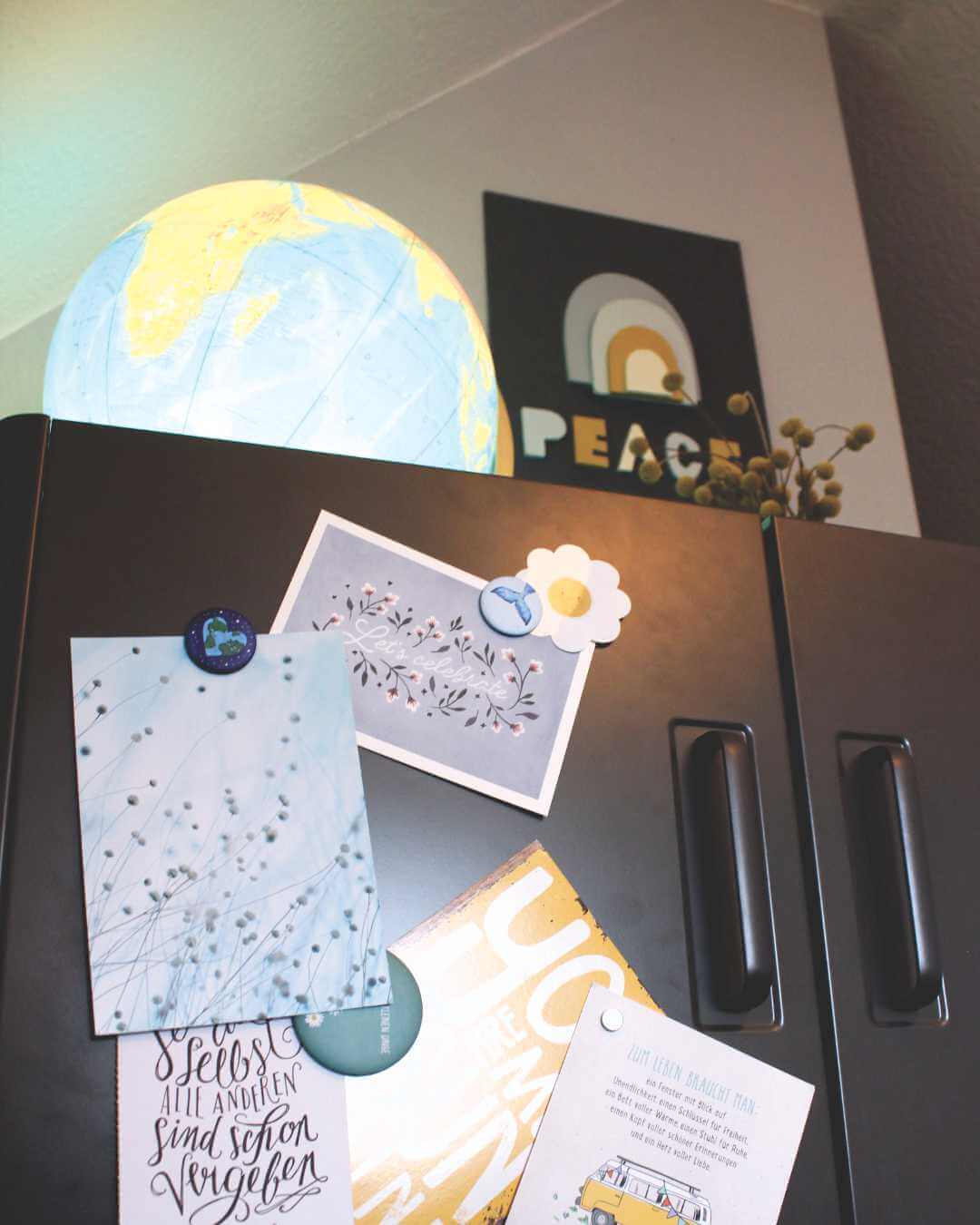 Metallschrank-grau-mit-globus-regenbogen-bild-und-postkarten-Atelier-Sintje-Tramm