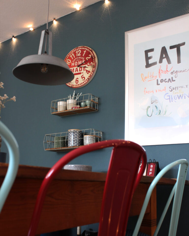 gemuetlich-eingerichtete-industrial-kueche-mit-lichterkette-holztisch-und-roter-Wanduhr-petrol-kirschrot-mintblau-Interior-Design-Sintje-Tramm