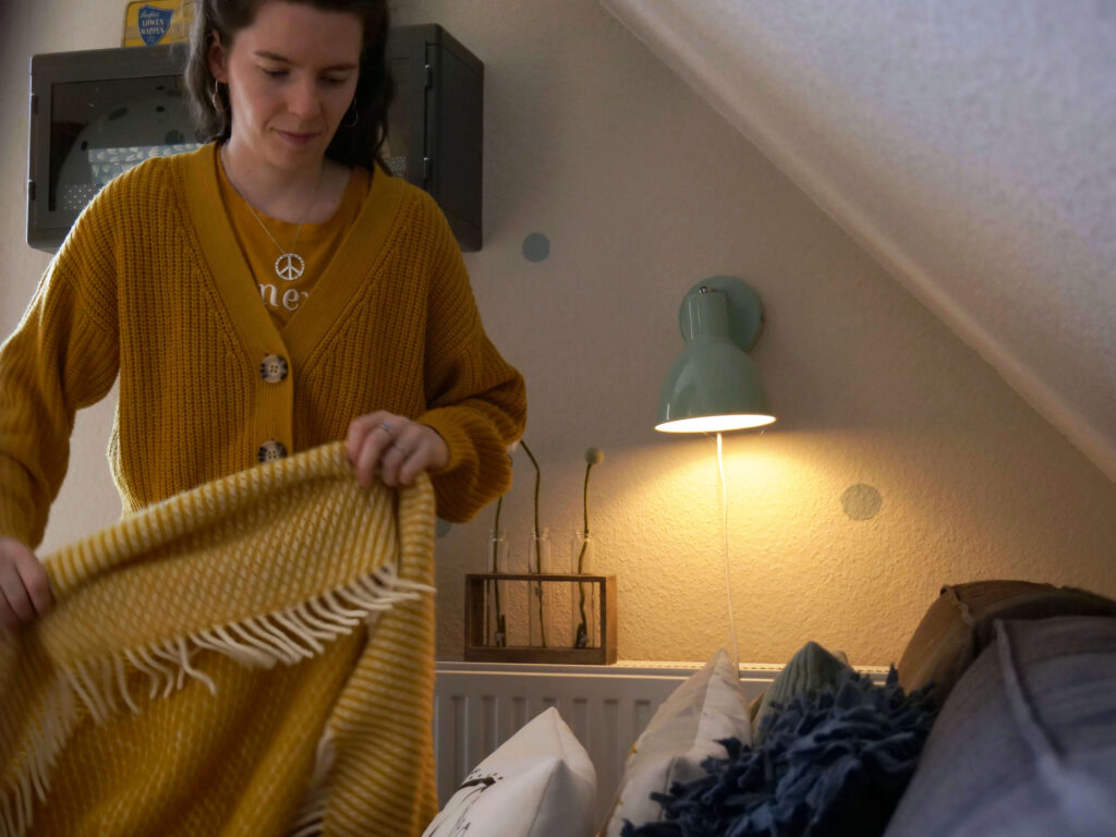 junge-frau-mit-decke-wohnzimmer-gelb-interior-design-sintje-tramm